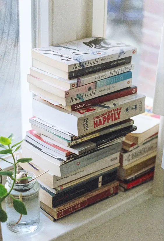 Een stapel boeken bij een raam